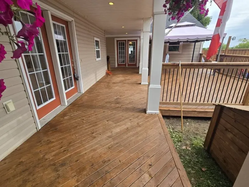 Newly stained pressure-treated wood deck with railing and posts.