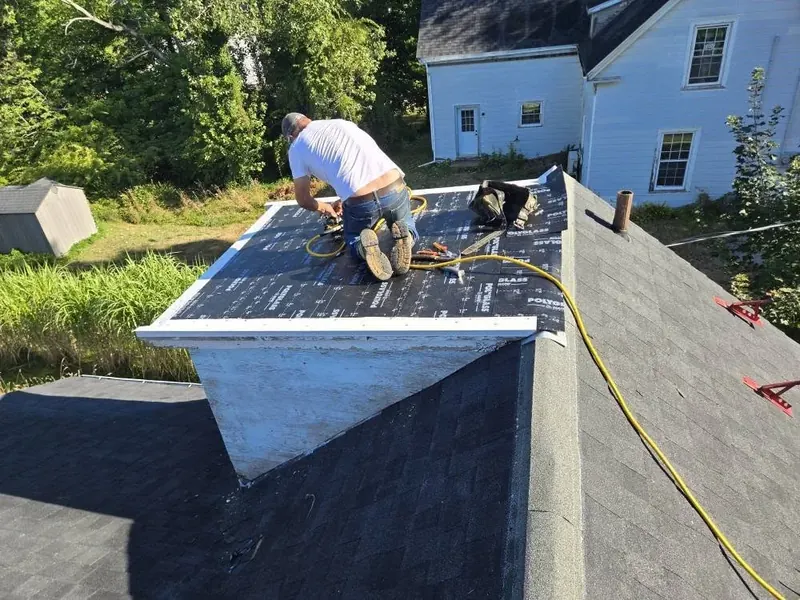 Worker installing membrane on a residential flat roof addition.