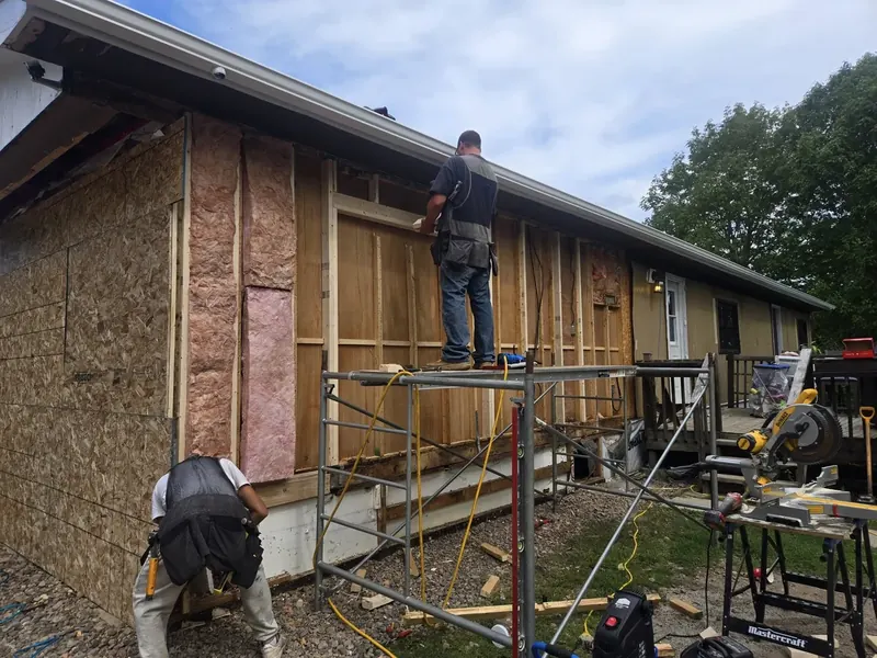 Worker on scaffolding installing soffit and fascia trim.